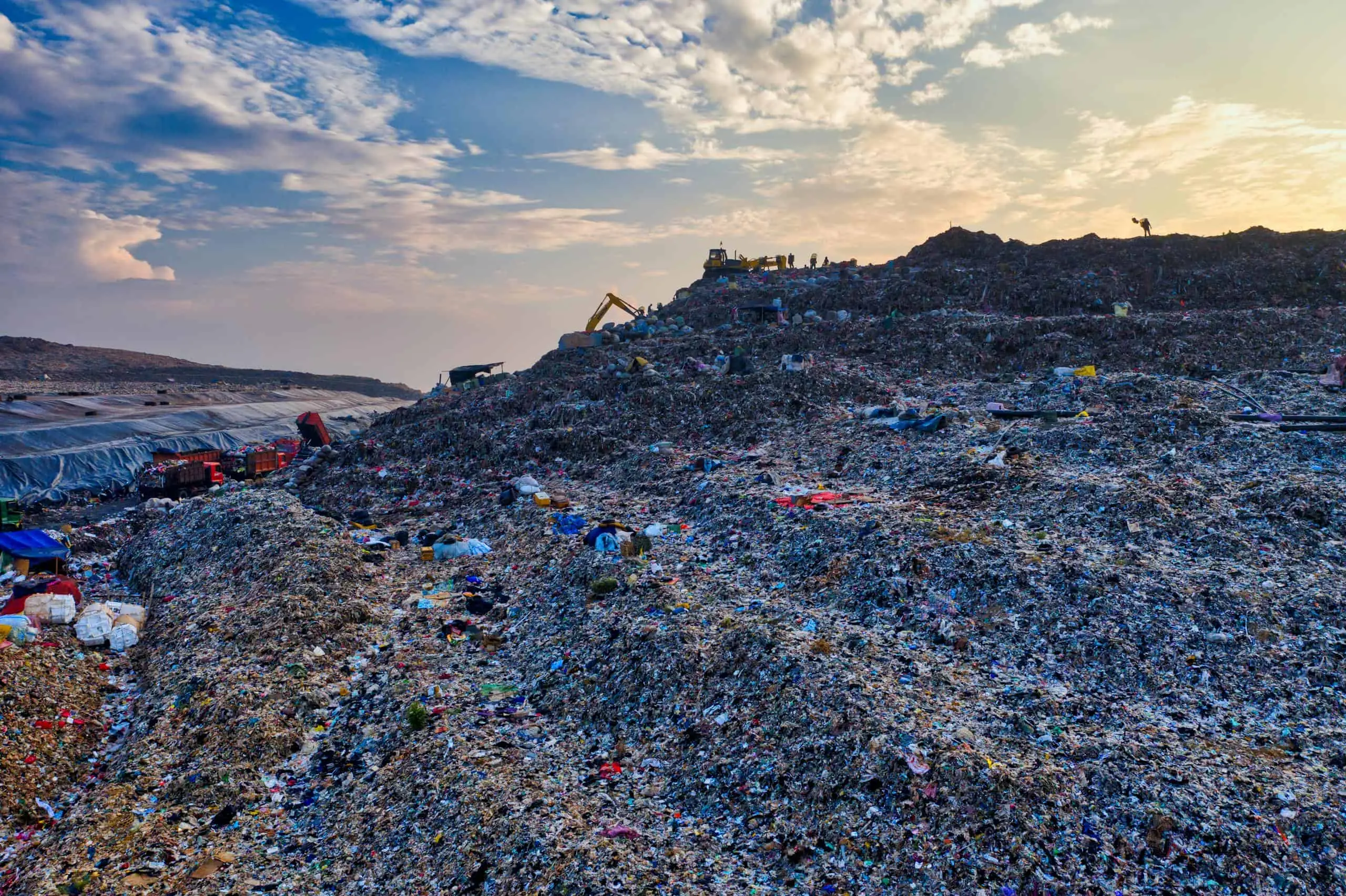 Expansive landfill site in West Java, Indonesia, showcasing environmental impact at sunset.